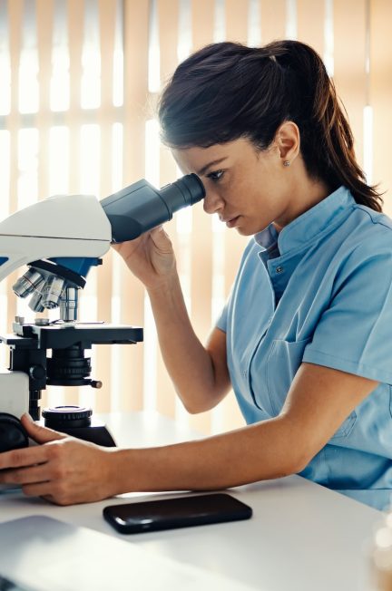 a lab assistant in lab using microscope for tests