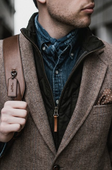 man in brown suit jacket carrying brown backpack