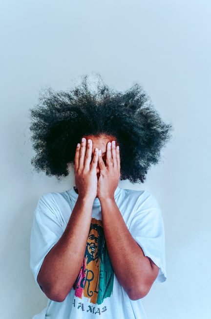 man in white t-shirt covering his face with his hair