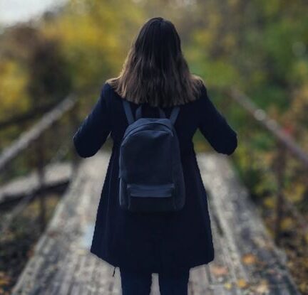 Solo Travel - Selective Focus Photography of Woman Wearing Black Overcoat Standing on Wooden Bridge